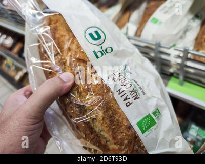 Puilboreau, France - October 14, 2020:Man buying organic cereal bread in the bakery section of a supermarket Stock Photo