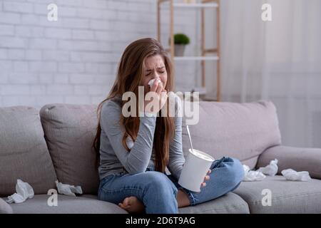 Brokenhearted young woman with bucket of ice cream crying while watching drama on TV at home Stock Photo