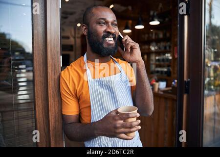 Joyful Afro American man talking on cellphone outdoors Stock Photo