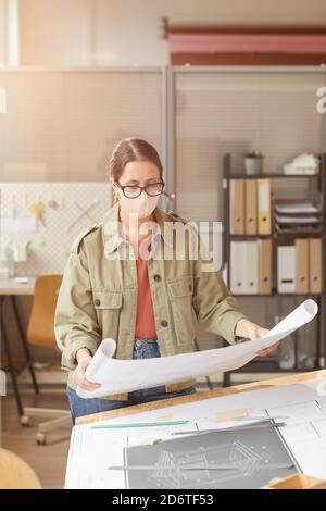 Portrait of female architect wearing mask while working at drawing desk in sunlight Stock Photo