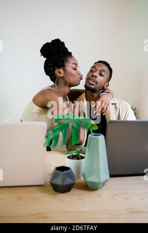 Happy young african american husband helps to wife in sportswear do ...