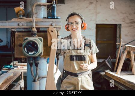 Woman carpenter in traditional carpentry adjusting the machine planer Stock Photo