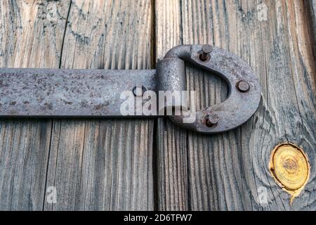 Metal door hinge with torn nails, on an old wooden gate Stock Photo