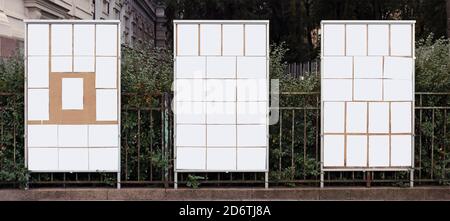 Three wooden information boards with blank paper sheets are installed on a city street Stock Photo