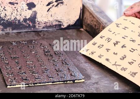 A man takes a printed sheet of paper. Cyrillic alphabet for printing in vintage style. Printing books old retro method. Stock Photo