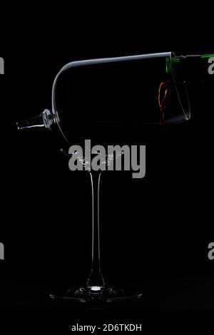 Red wine is poured into a broken glass silhouette on Black Background. High quality photo.  Stock Photo
