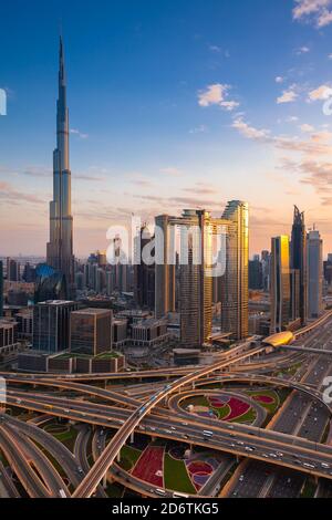 The futuristic view of Dubai skyline at dusk with Sheikh Zayed road and Dubai Metro on the foreground Stock Photo