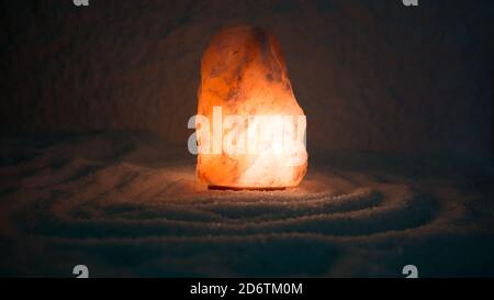 Salt lamp on the floor strewn with salt. Stock Photo