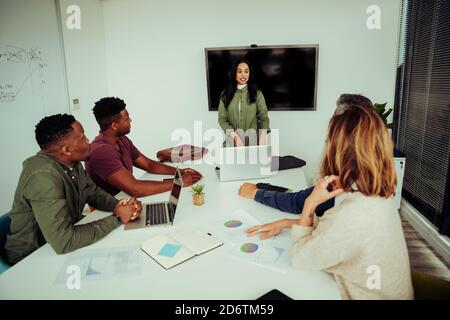 Female business woman searching for presentation on laptop before speaking to clients sitting in board room Stock Photo
