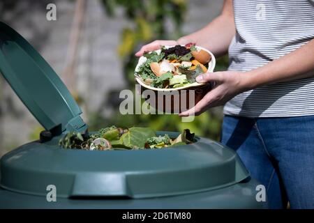 Close Up Of Woman Emptying Food Waste Into Garden Composter At Home Stock Photo