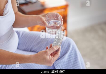 Close Up Of Mature Woman Sitting On Bed Wearing Pyjamas Taking Medication Stock Photo