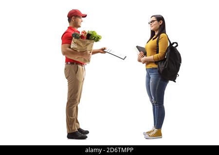 Full length profile shot of a delivery man holding groceries in a paper bag and giving a document to a female student isolated on white background Stock Photo
