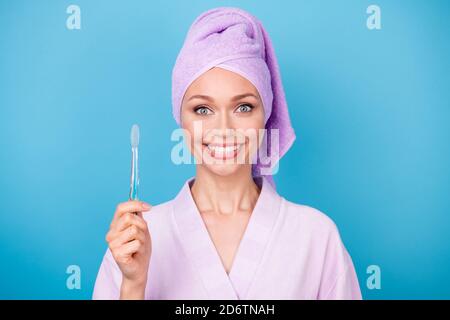 Photo of lovely lady hold toothbrush toothy shiny white smiling wear purple towel turban bathrobe isolated blue color background Stock Photo