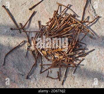 Heap of rusty  curved  nails are piled on granite  stone. Stock Photo