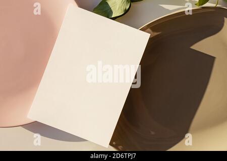 Blank paper card mock-up in minimal style. Plates and paper in natural sunlight. Wedding invitation, menu or other print product template Stock Photo