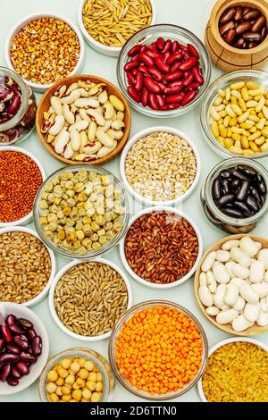 Assorted different types of beans and cereals grains. Set of indispensable sources of protein for a healthy lifestyle. Light green background, top vie Stock Photo