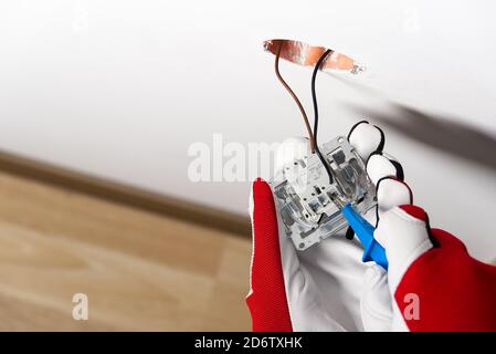 electrician installing light switch on painted wall with screwdriver. Man installing light switch after home renovation. Stock Photo