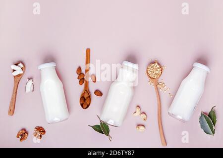 Different types of vegan plant based non-dairy milk in small glass bottles on pink background Stock Photo