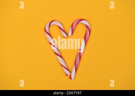 Candy canes shaped as a heart on a yellow background Stock Photo