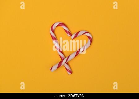 candy canes shaped as a heart isolated on a yellow background Stock Photo