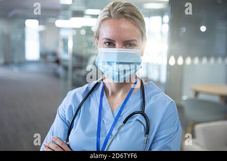 A healthcare professional, wearing a medical mask and scrubs, performs ...