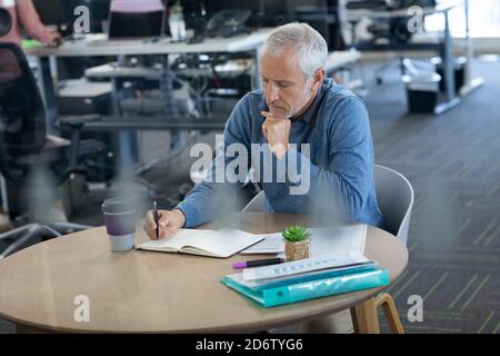 Senior businessman taking notes at office Stock Photo
