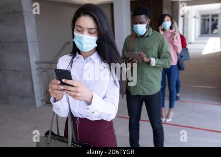 Group of people wearing face masks using smartphones while standing in queue Stock Photo