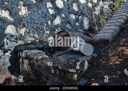 Gas mask on wall and rusty barrel of crude oil Stock Photo