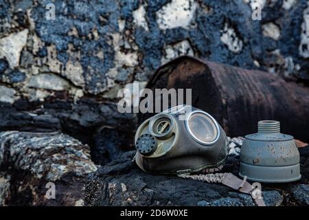 Gas mask with rusty barrel background and black brick wall Stock Photo