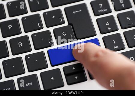 Computer keyboard with one of the blue keys with finger pressing it Stock Photo