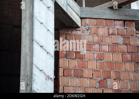 Close up on a construction site of two walls of a residential buildings, made of two building materials: one in cement and concrete, the other in red Stock Photo