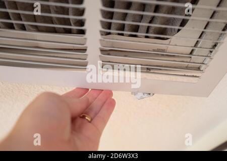 Hand of a man opening air intake to remove soiled HVAC filter during replacement of a domestic air conditioner and heating system filter, used to capture smoke and allergens, in a domestic home, San Ramon, California, September 12, 2020. () Stock Photo