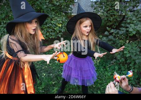 Little children trick or treating. Two little witches scare the neighborson on Halloween Stock Photo