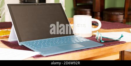 Computer is set up with glasses close by to work from home during the COVID-19 Coronavirus pandemic. Stock Photo