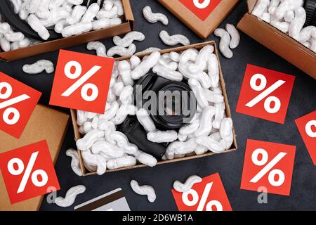 Online shopping of electronic products during sales period concept. Cardboard box with camera and protective foam pads inside on black background. Fla