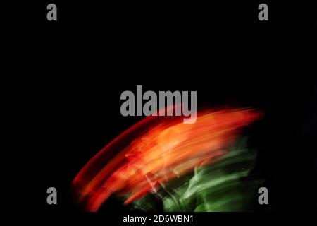 red flowers in motion blur against black background, natural sunlight and long exposure Stock Photo