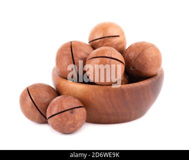 Macadamia nuts in wooden bowl, isolated on white background. Unshelled macadamia. Stock Photo