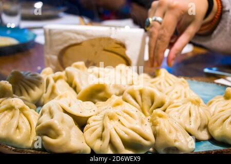 Georgian khinkali on the table and hand in restourant Stock Photo