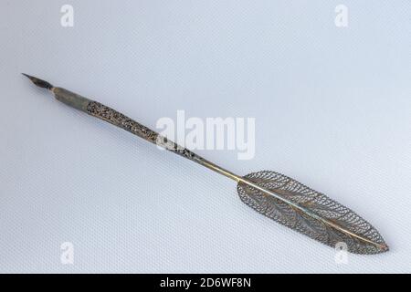 Old ink pen with metal filigreed and ink bottle isolated on white background. Vintage calligraphy pen and bottle of ink. Stock Photo