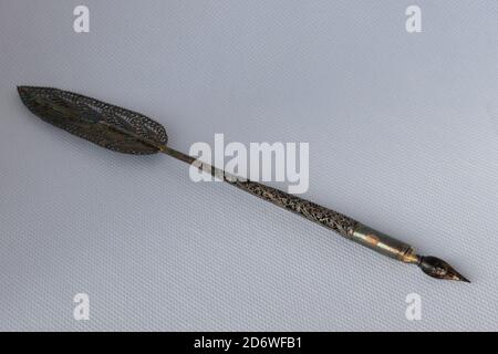 Old ink pen with metal filigreed and ink bottle isolated on white background. Vintage calligraphy pen and bottle of ink. Stock Photo