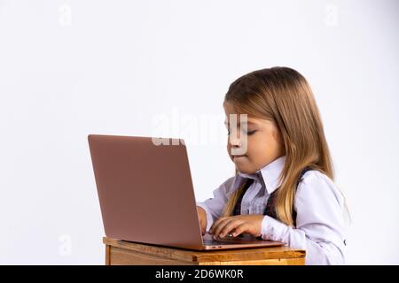 Online education for children. A schoolgirl teaches the school curriculum using a laptop. Photo on the white background Stock Photo
