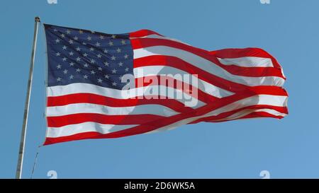 American USA flag on a flagpole waving in the wind Stock Photo