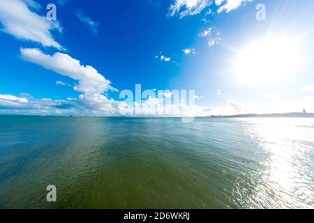 View of fast moving clouds front of the blue sky above the river Tejo as boats pass by in Lisbon, Portugal. Stock Photo