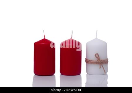 two red candles and one white candle in a jute rope, isolated on a white background Stock Photo