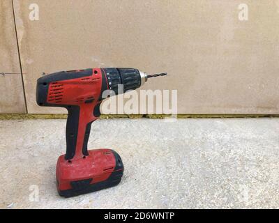 Cordless screwdriver on concrete surface against drywall. Electric power tools Stock Photo