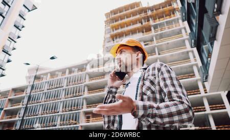 Engineer talking on phone. Architect using phone on construction site. Foreman phone call control process. Construction worker communications in Stock Photo
