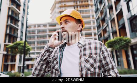Engineer talking on phone. Architect using phone on construction site. Foreman phone call control process. Construction worker communications in Stock Photo