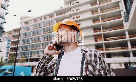 Engineer talking on phone. Architect using phone on construction site. Foreman phone call control process. Construction worker communications in Stock Photo