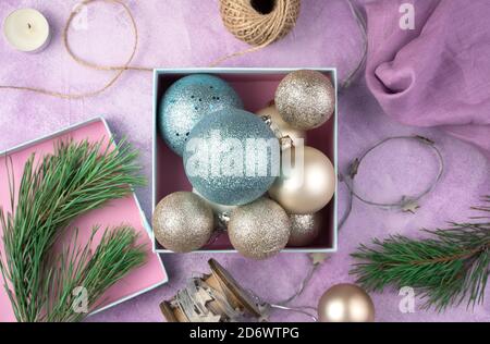 Christmas balls of different shapes and colors in a gift box on a pink background. Stock Photo