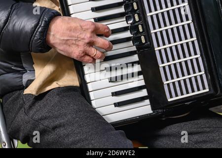 An elderly man plays the accordion. close-up musician playing the accordion on the street. Stock Photo
